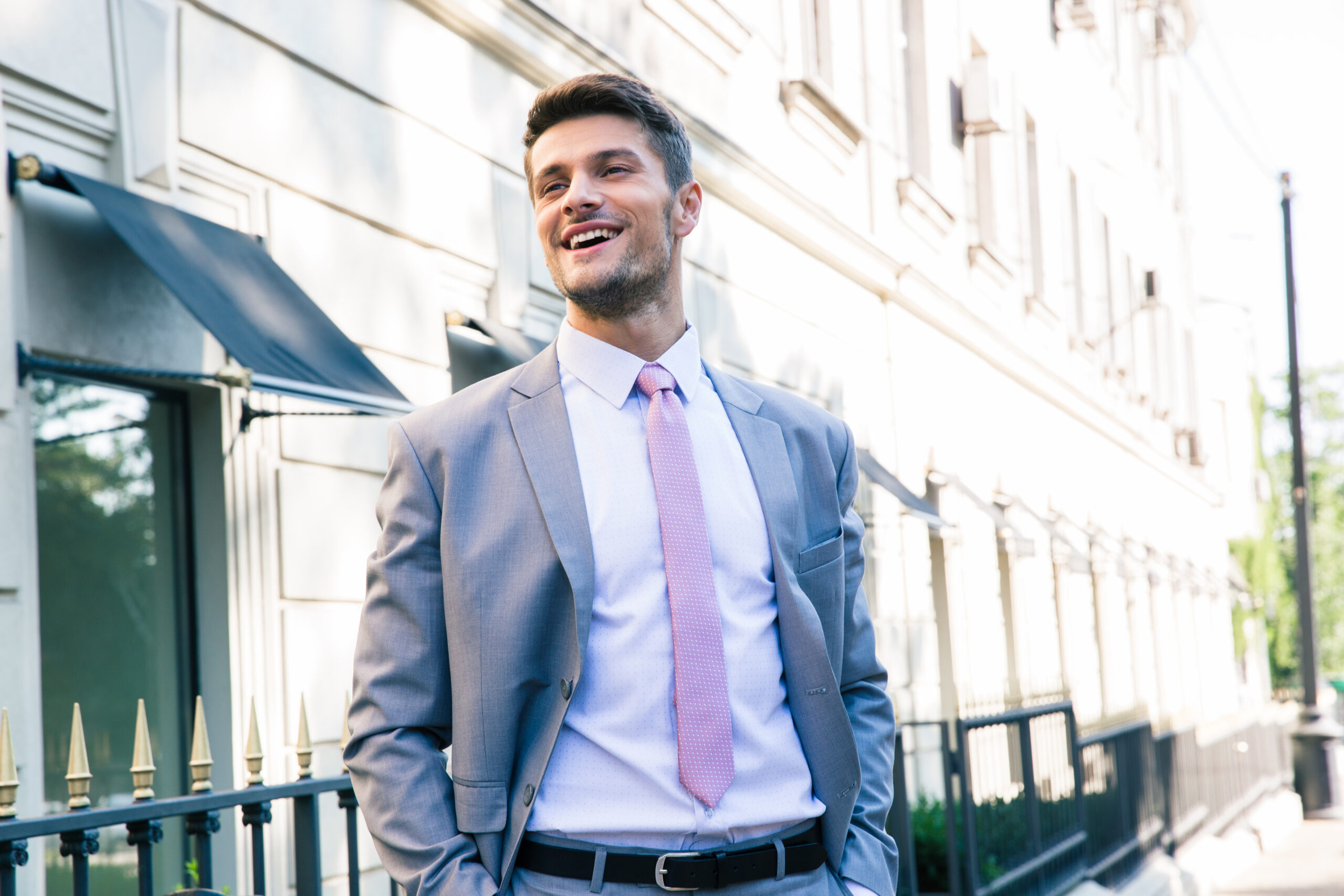 Laughing young businessman standing outdoors in the city